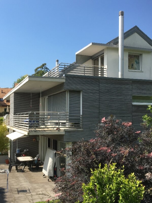 Maison de trois étages grise et blanche avec terrasse au rez de chaussée