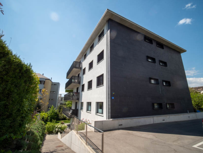 Façade d'un bâtiment gris avec quatre balcons de couleur noire