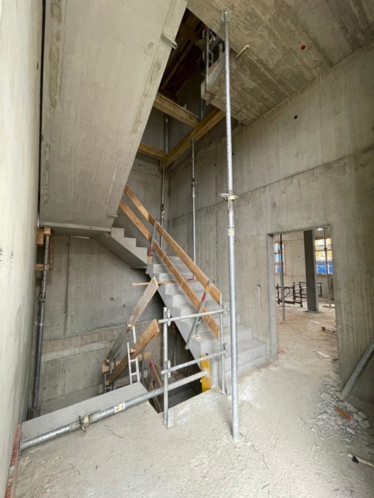 cage d'escalier en construction, couleur béton et rampe en bois - Tolochenaz projet Minergie de 14 logements - façade de l'immeuble