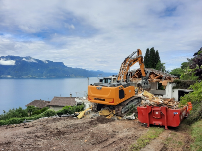deux machines de chantier, une orange, l'autre rouge devant le lac léman en fond, sol en chantier pour le nouveau projet à Chardonne "Les Chardonnerets"